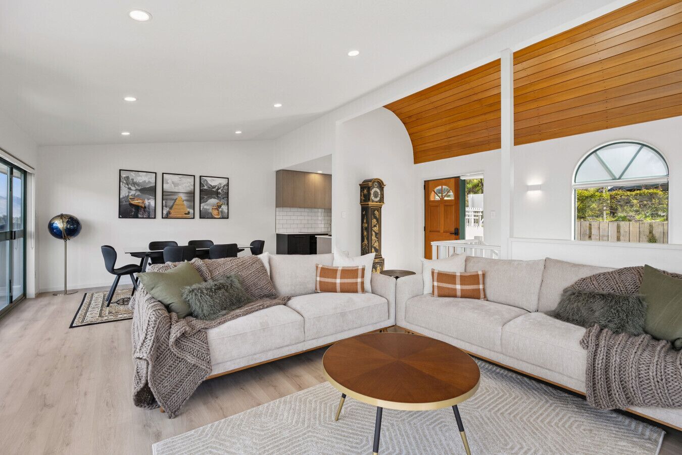 A modern living room with a sectional sofa, a coffee table, and a dining area with chairs.