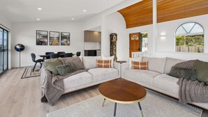 Una sala moderna con un sofá modular, una mesa de centro y un comedor con sillas.