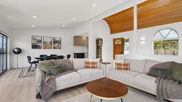 A modern living room with a sectional sofa, a coffee table, and a dining area with chairs.