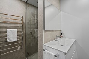 Une salle de bain moderne avec une douche à parois de verre, un lavabo blanc et un porte-serviettes.