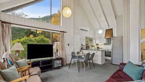 Ein modernes Wohnzimmer mit Fernseher, Sitzgelegenheiten und Essbereich.