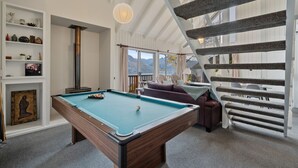 Ein Billardtisch, eine Couch, eine Treppe und Blick ins Freie.