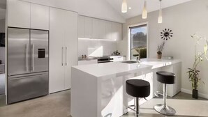 Una cocina moderna con una isla grande, electrodomésticos de acero inoxidable e iluminación colgante.