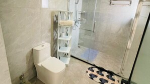 Ein modernes Badezimmer mit Toilette, einer gläsernen Dusche und einem weißen Handtuchhalter.