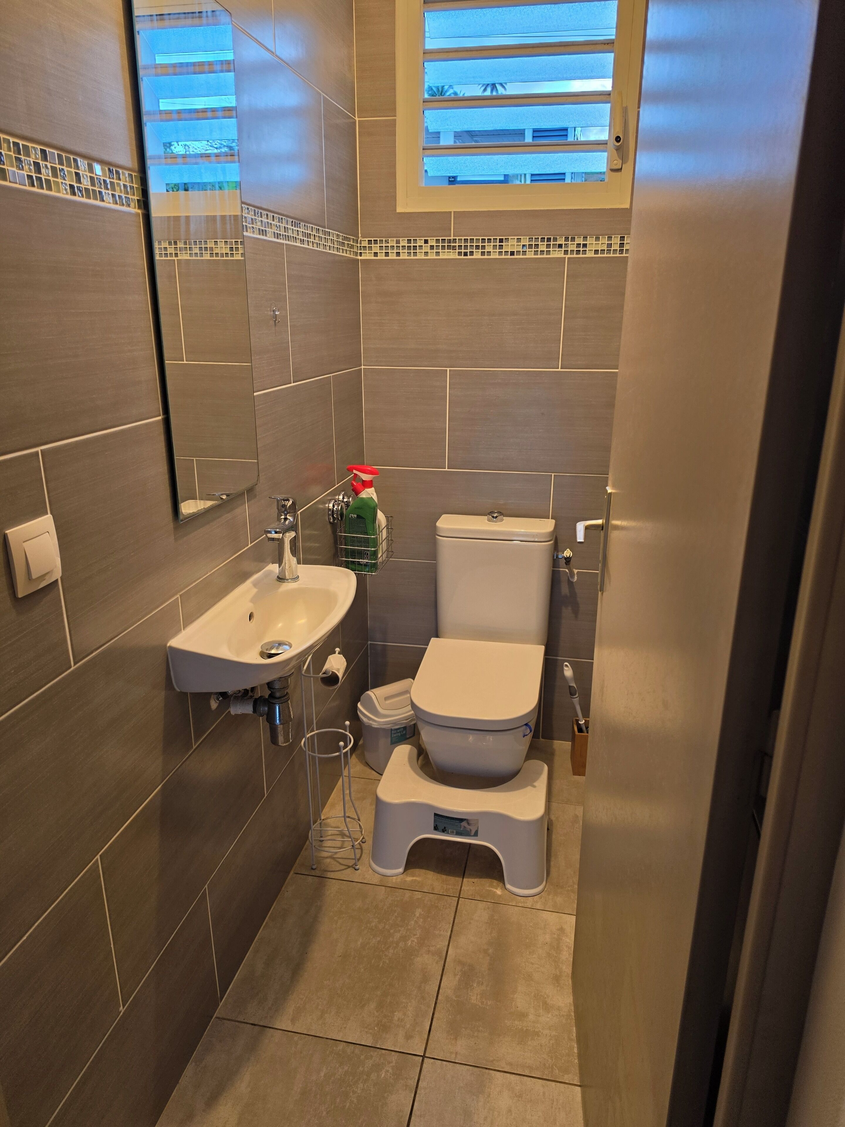 A modern bathroom with a toilet, sink, and window.