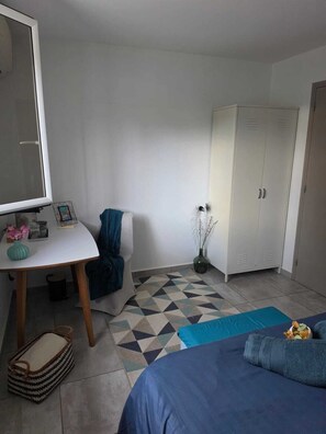 Een slaapkamer met een bed, bureau, kast en een vloer met patroon.