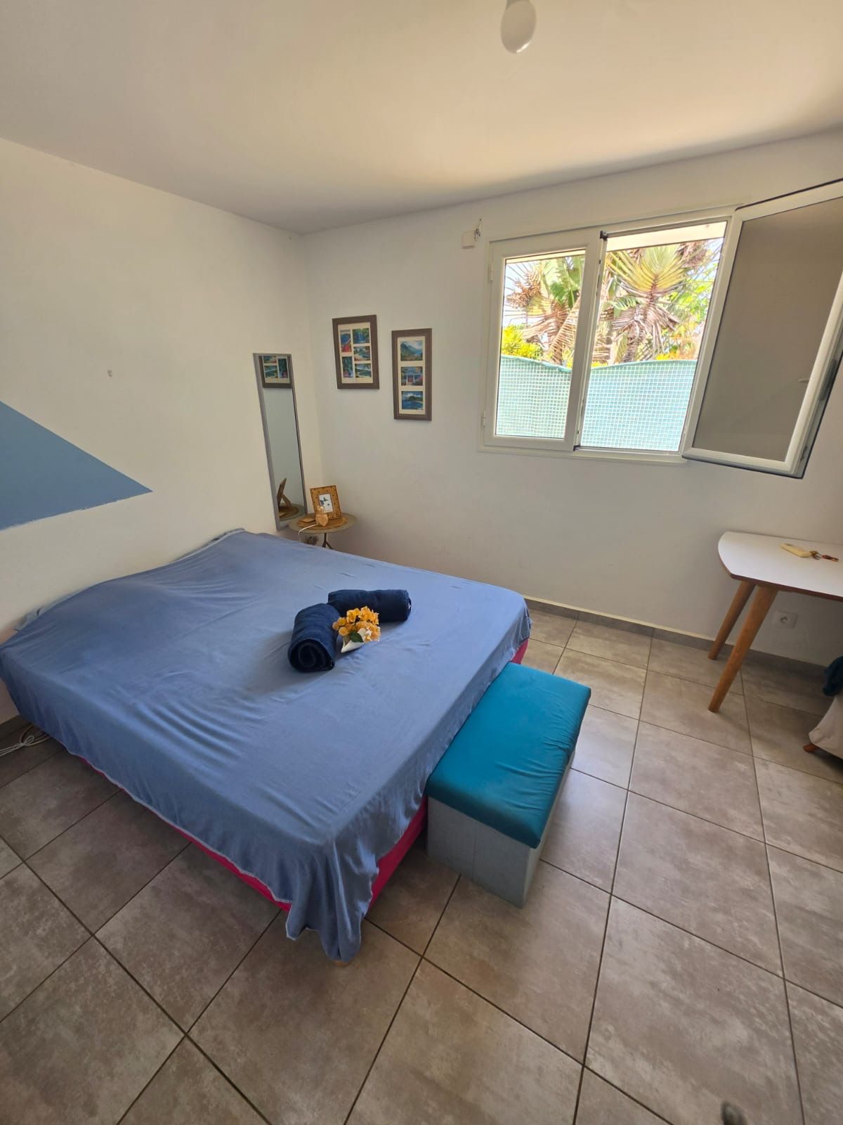 Une chambre à coucher avec un lit, un banc, un bureau et une fenêtre.