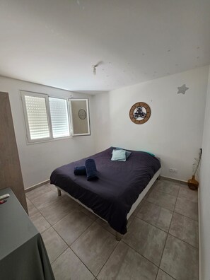 A bedroom with a bed, a wall clock, and a window with blinds. - Bed and breakfast Petit-Bourg (Petit-Bourg)