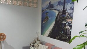 Een woonkamer met een grijze bank, decoratieve kussens, een aan de muur bevestigd kunstwerk en een vloerlamp.