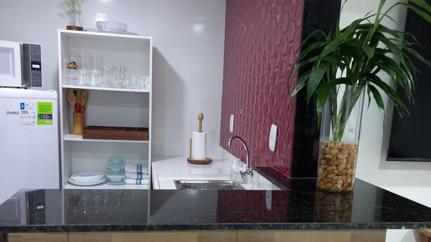 Een moderne keuken met een zwart aanrecht, houten krukken, een spoelbak en een plant in pot.