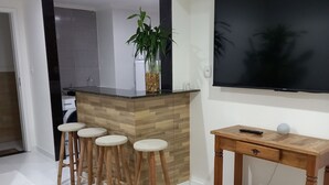 Een moderne keuken met houten krukken, een bar, een grote flatscreen-tv en een vloerkleed met een patroon.