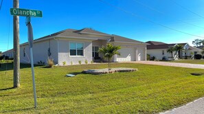 A residential house with a garage, a small lawn, and a street sign. - 4-bedroom house with 3 bathrooms, a 3-car garage, and plenty of open space. (Punta Gorda)