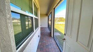 A narrow corridor with a brick floor, large windows, and a door leading outside. - 4-bedroom house with 3 bathrooms, a 3-car garage, and plenty of open space. (Punta Gorda)