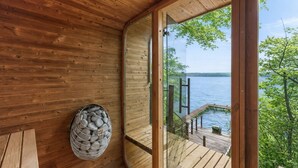 Una cabaña de madera con un ventanal de vidrio que da a una terraza con vistas a un lago.