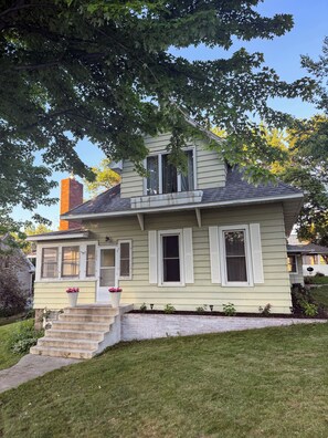 A two-story house with a front porch, a chimney, and a well-maintained lawn. - Charming cottage just steps from the lake and downtown Battle Lake (Battle Lake)