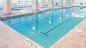 An indoor swimming pool with clear water, tiled floor, and a view of the sky through large windows. - Oceanfront Apartment  Daytona Beach for rent (Daytona Beach)