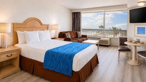 A hotel room with a large bed, a sofa, a small table, and a TV. - Oceanfront Apartment  Daytona Beach for rent (Daytona Beach)