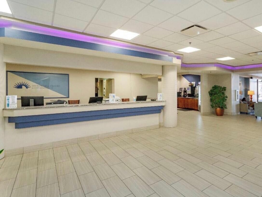 A reception area with a counter, computers, and a framed logo on the wall.