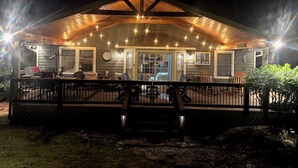 Un espace extérieur abrité, doté d’une terrasse en bois, de sièges et de guirlandes lumineuses.