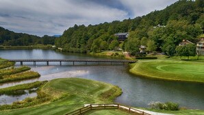 Un parcours de golf avec un pont, des plans d’eau et des maisons résidentielles en arrière-plan.