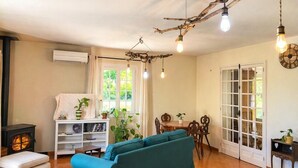 A cozy living room with a sofa, a fireplace, a dining area, and a large window. - Villa La Graine de Vie with shared pool (LE THORONET)