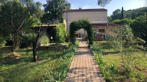 A pathway leading to a building with a tiled roof, surrounded by greenery and trees. - Villa La Graine de Vie with shared pool (LE THORONET)