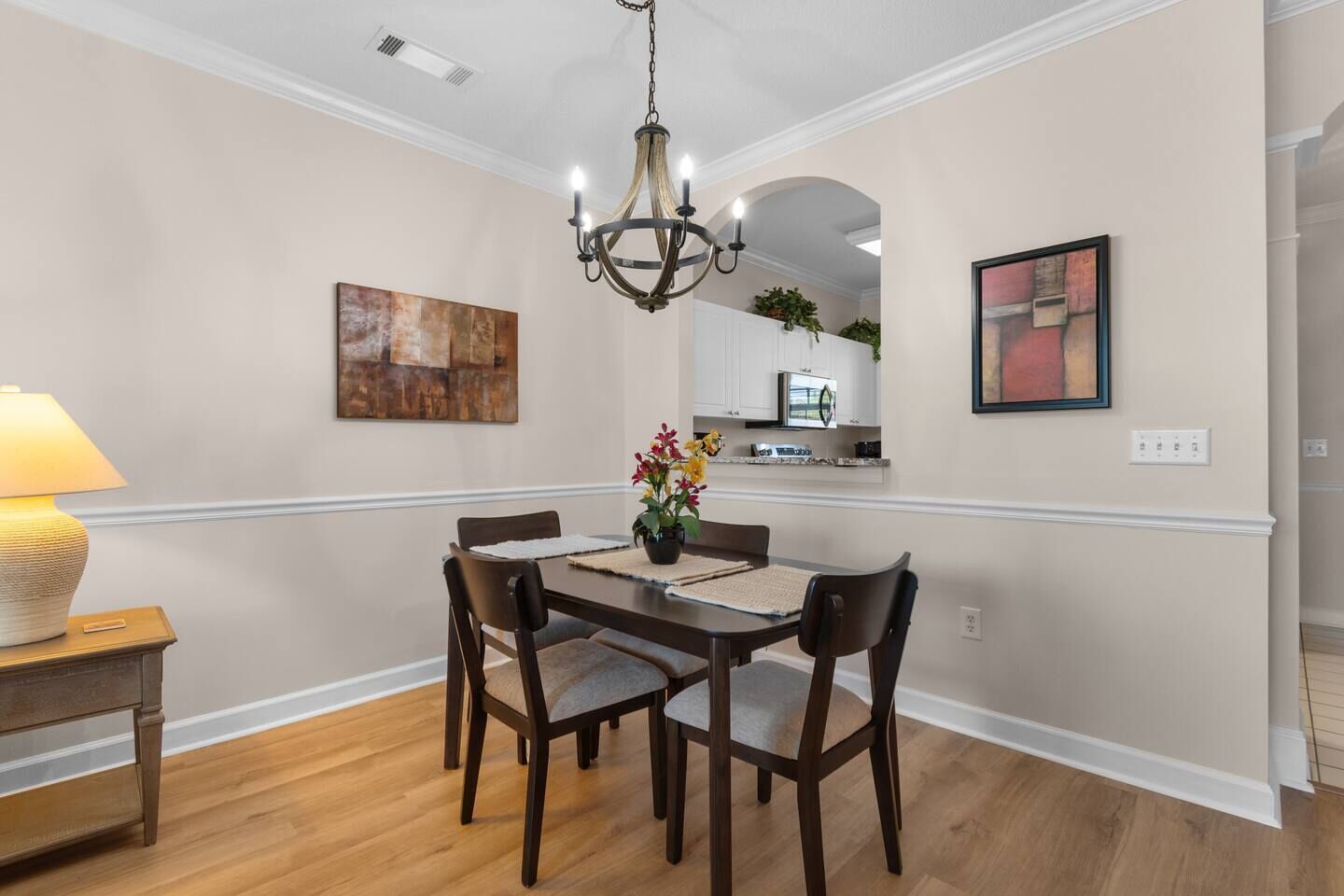 A dining area with a chandelier, wooden chairs, a table, and artwork on the walls.