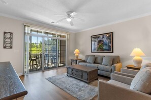 A living room with a sofa, armchairs, a coffee table, a dining table, and a ceiling fan. - Golf Course View | Spacious Coastal living (North Myrtle Beach)