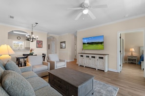 A living room with a sofa, a coffee table, a TV, and a ceiling fan. - Golf Course View | Spacious Coastal Living (North Myrtle Beach)