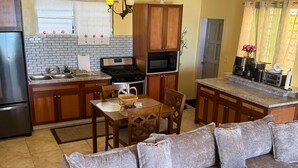 Una cocina con comedor, armarios de madera, un refrigerador, una estufa y un microondas.