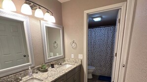 A bathroom with a granite countertop, double sink, large mirror, and a shower curtain. - Cozy 2-bedroom condo in perfect Branson with AC (Branson)