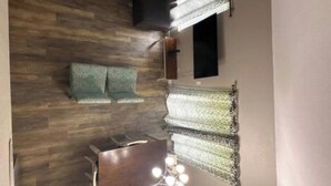 A living room with a dark-colored sofa, a wooden floor, a small table with a keyboard, and a wall-mounted light fixture. - Cozy 2-bedroom condo in perfect Branson with AC (Branson)