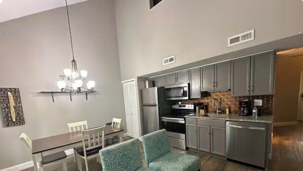 A modern kitchen with stainless steel appliances, a dining area with a table and chairs, and a patterned sofa. - Cozy 2-bedroom condo in perfect Branson with AC (Branson)