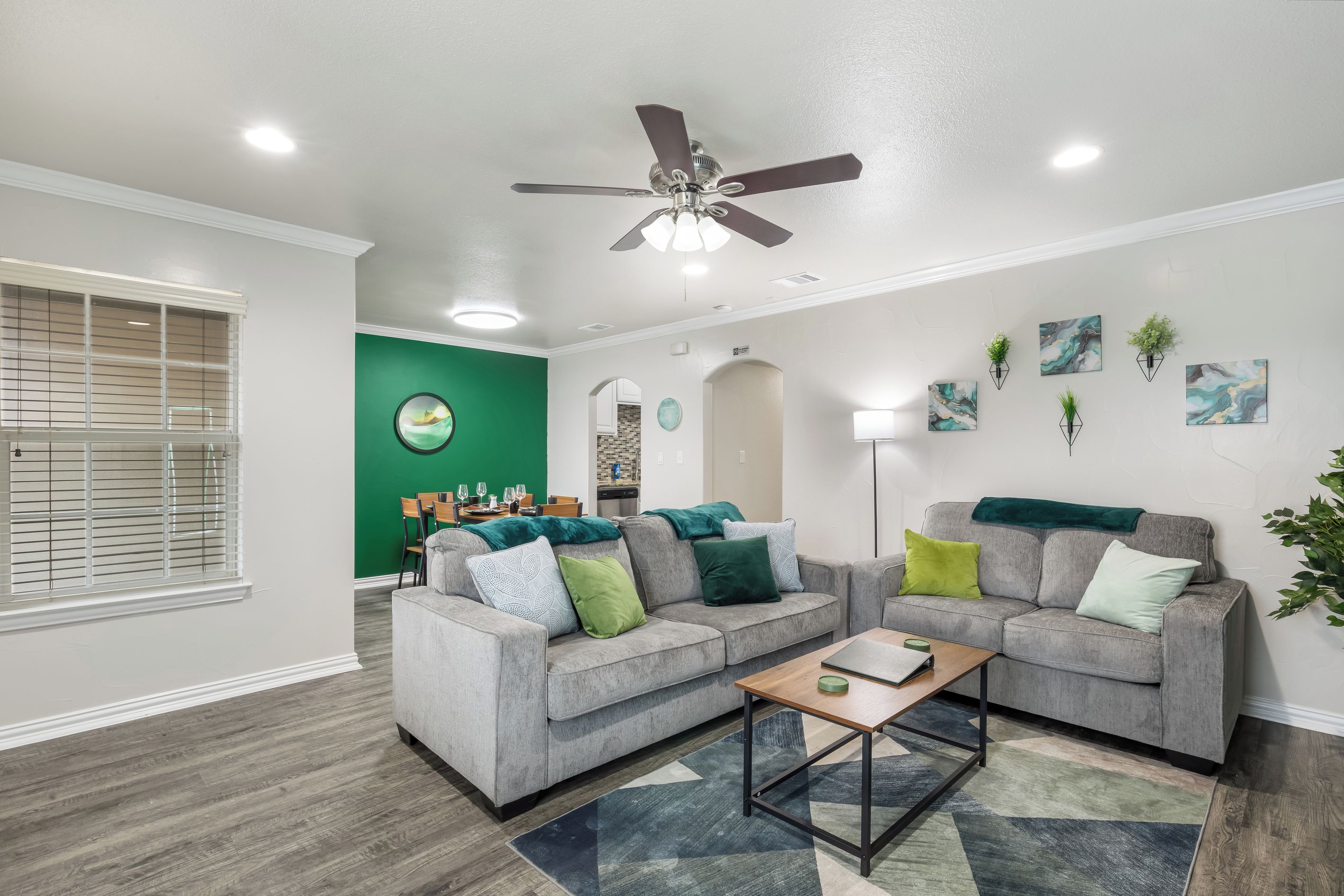 A modern living room with two grey sofas, a coffee table, and a ceiling fan.