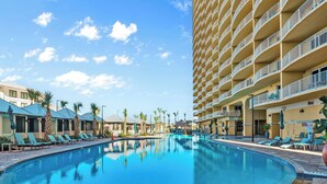 Et hotel med swimmingpool, liggestole og en bygning med flere etager og balkoner.