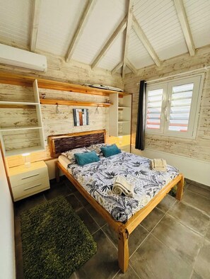 Ein Schlafzimmer mit einem hölzernen Bett, einem Nachttisch, einem Regal und einem Fenster mit Jalousien.
