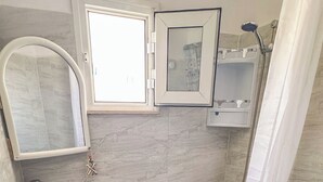 Ein Badezimmer mit Waschbecken, Toilette, Dusche und einem kleinen Fenster.