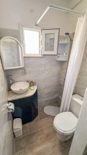 Ein Badezimmer mit Waschbecken, Toilette, Dusche und einem kleinen Fenster.