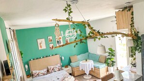 Ein gemütliches Schlafzimmer mit Bett, Nachttischen, einer kleinen Sitzecke und einer Küchenzeile.