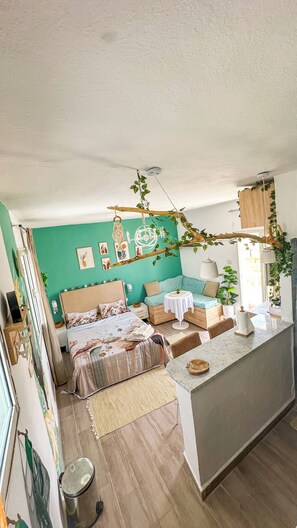 Ein gemütliches Schlafzimmer mit Bett, Nachttischen, einer kleinen Sitzecke und einer Küchenzeile.