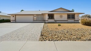 A single-story house with a garage, a small porch, and a star-shaped decoration on the wall. - Tranquil Sun City West 2BR | 55+ Community Pool (Sun City West)