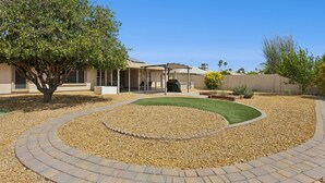 A residential property with a landscaped garden, a patio area, and a covered outdoor space. - Tranquil Sun City West 2BR | 55+ Community Pool (Sun City West)