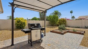 A covered patio with a grill, a water cooler, and a brick patio. - Tranquil Sun City West 2BR | 55+ Community Pool (Sun City West)