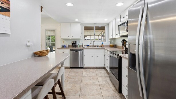 A modern kitchen with white cabinets, stainless steel appliances, and a large refrigerator. - Tranquil Sun City West 2BR | 55+ Community Pool (Sun City West)