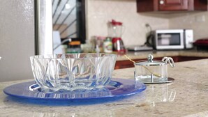A kitchen with a blue glass dish, a clear glass container, and wooden cabinets. - Large House With AC Wifi Parking Ideal for Families (San Juan de la Maguana)