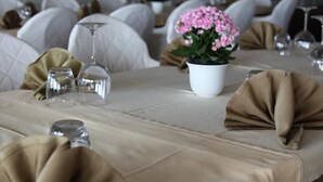 Een gedekte tafel met een witte tafelkleed, een plant in pot en gevouwen servetten.