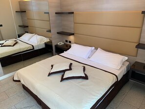 A hotel room with a large bed, a bedside table with a phone, and a mirror reflecting the room. - Hotel San Carlo (Lignano Sabbiadoro)
