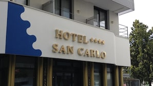 Een hotel genaamd 'HOTEL SAN CARLO' met een opvallend bord en een balkon.