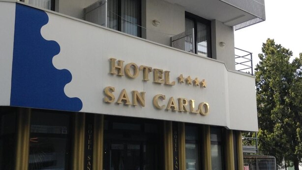 A hotel named 'HOTEL SAN CARLO' with a prominent sign and a balcony. - Hotel San Carlo (Lignano Sabbiadoro)