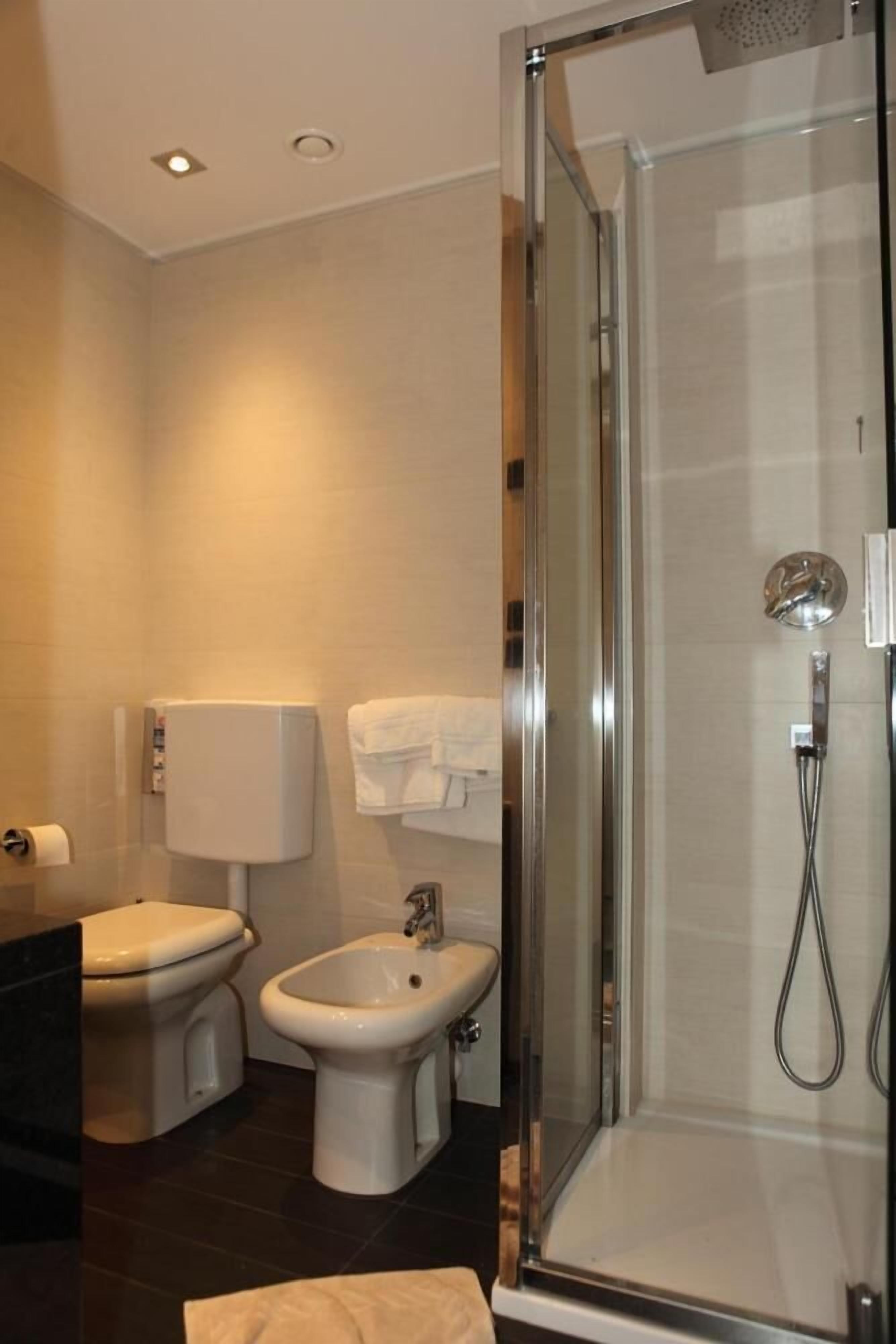 A modern bathroom with a glass-enclosed shower, a toilet, and a bidet.